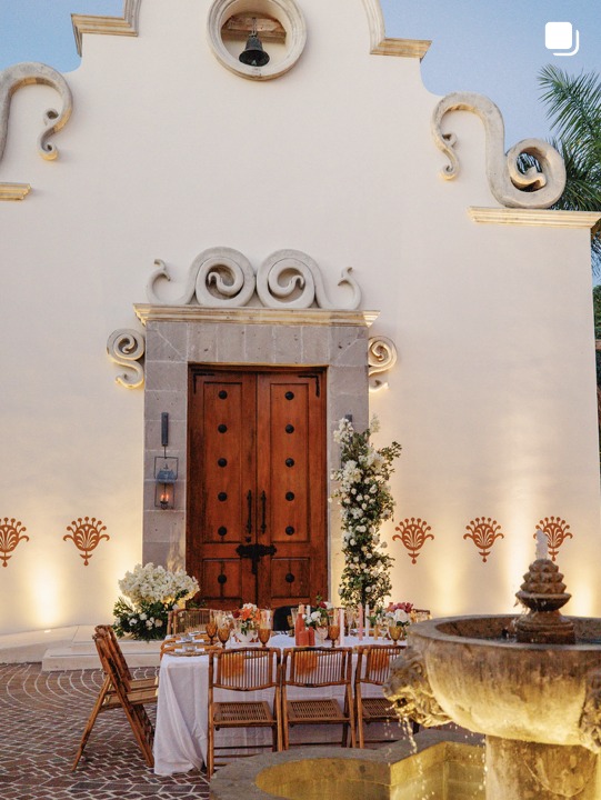 Mesa de boda en patio con fuente y flores blancas